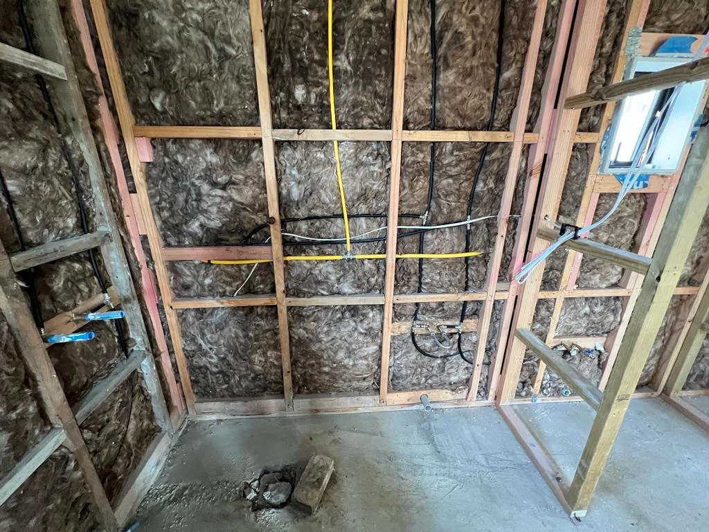 Bathroom stripped to framing and insulation with rough-in plumbing during an Auckland renovation