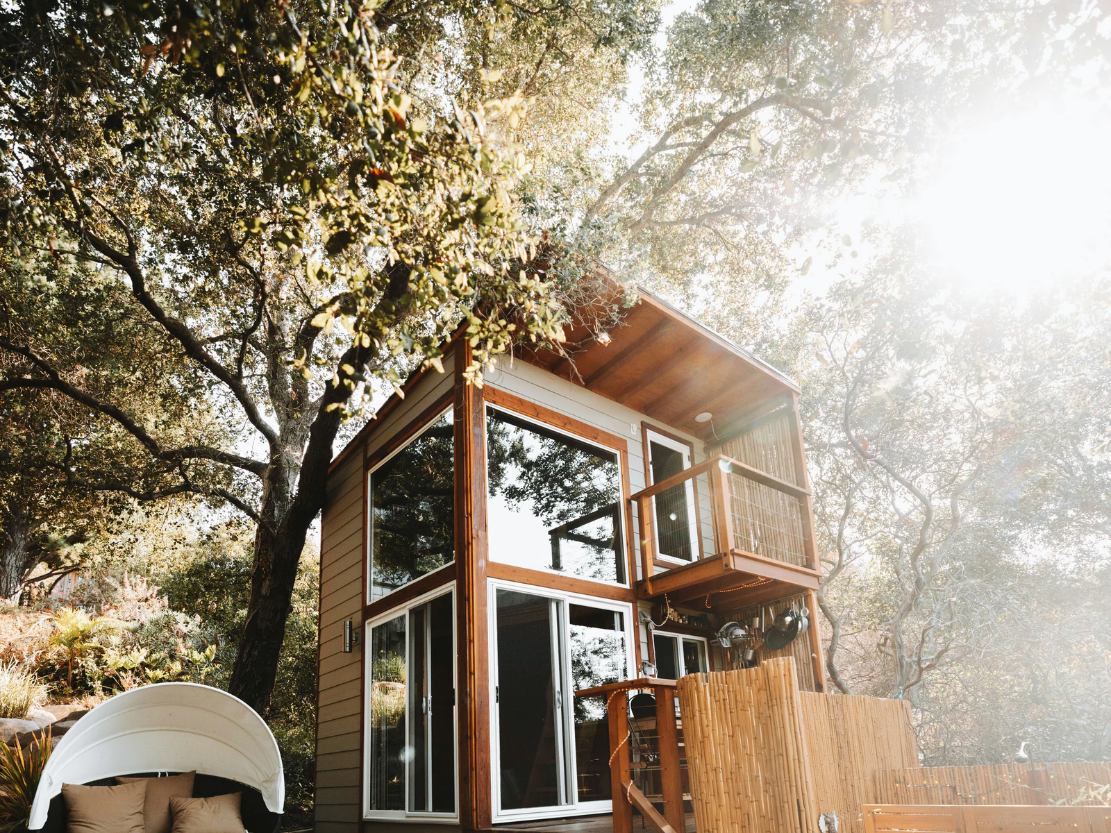 Tiny home raised on a deck with full-height glazing and outdoor seating